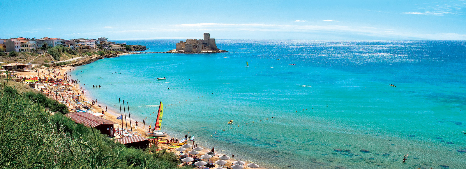 Il Castello Aragonese sullo sfondo di un mare cristallino